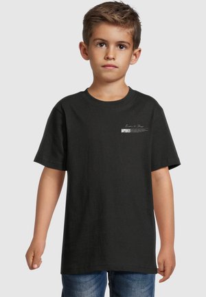 Camiseta de algodón negra con mangas cortas, ajuste holgado, escote redondo, que presenta un pequeño estampado gráfico blanco en la parte izquierda del pecho.