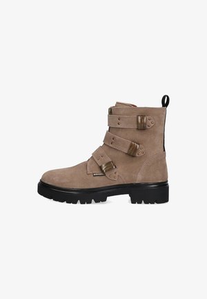 Bruine nubuck enkellaars met drie banden en metalen gespen. Stevige zwarte rubberen zool met een getextureerde loopvlak. Zijkantrits voor gemakkelijke instap.