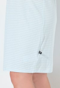 Abito in cotone azzurro chiaro con strisce bianche, orlo arrotondato e piccola etichetta di marca nera sul lato. Tessuto morbido, design casual.