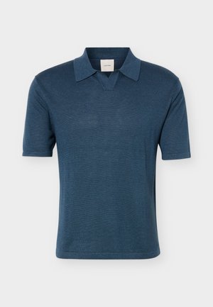 Rövid ujjú, sötétkék kötött galléros póló nyitott V-nyak kialakítással, egyszínű világosszürke háttéren bemutatva.