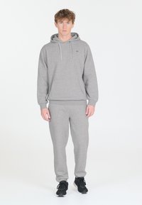 Huppari ja housut setti pehmeästä materiaalista. Ominaisuuksiin kuuluu etutasku ja nyörit. Yhdistetty mustiin urheilujalkineisiin.