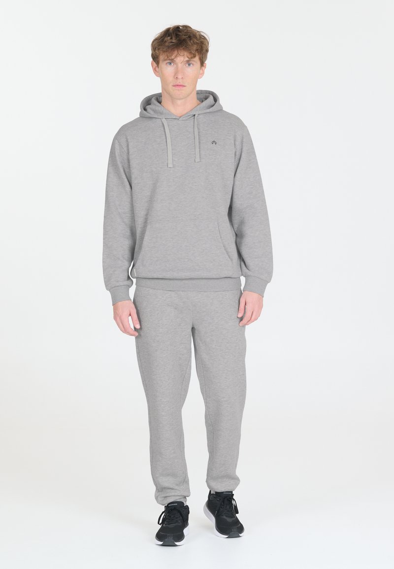 Huppari ja housut setti pehmeästä materiaalista. Ominaisuuksiin kuuluu etutasku ja nyörit. Yhdistetty mustiin urheilujalkineisiin.