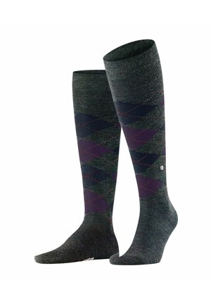 Kniestrümpfe in Dunkelgrün mit einem Argyle-Muster, das lila und blaue Rauten zeigt, akzentuiert durch rote Nähte und ein Logodetail.