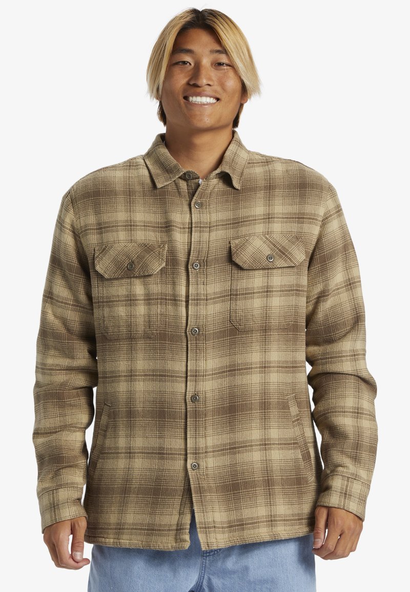 Brun og beige ternet flannel skjorte med knaplukning foran, to brystlommer og en afslappet pasform. Blød tekstur og lange ærmer.