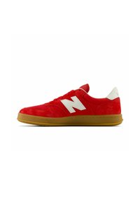 Red suede sneaker with white logo, featuring a rubber gum sole, lace-up design, and padded ankle for support.