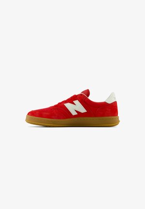 Sneaker rossa in suede con logo bianco, caratterizzata da una suola in gomma, design con lacci e caviglia imbottita per supporto.