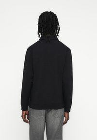 Μαύρο μακρυμάνικο πουλόβερ με γιακά, κατασκευασμένο από λείο ύφασμα. Διαθέτει ριμπ μανσέτες και τελείωμα, συνδυασμένο με ανοιχτό γκρι τζιν.