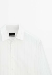 Chemise blanche à manches longues avec fines rayures verticales gris clair, col classique et boutons blancs, étiquetée Massimo Dutti.