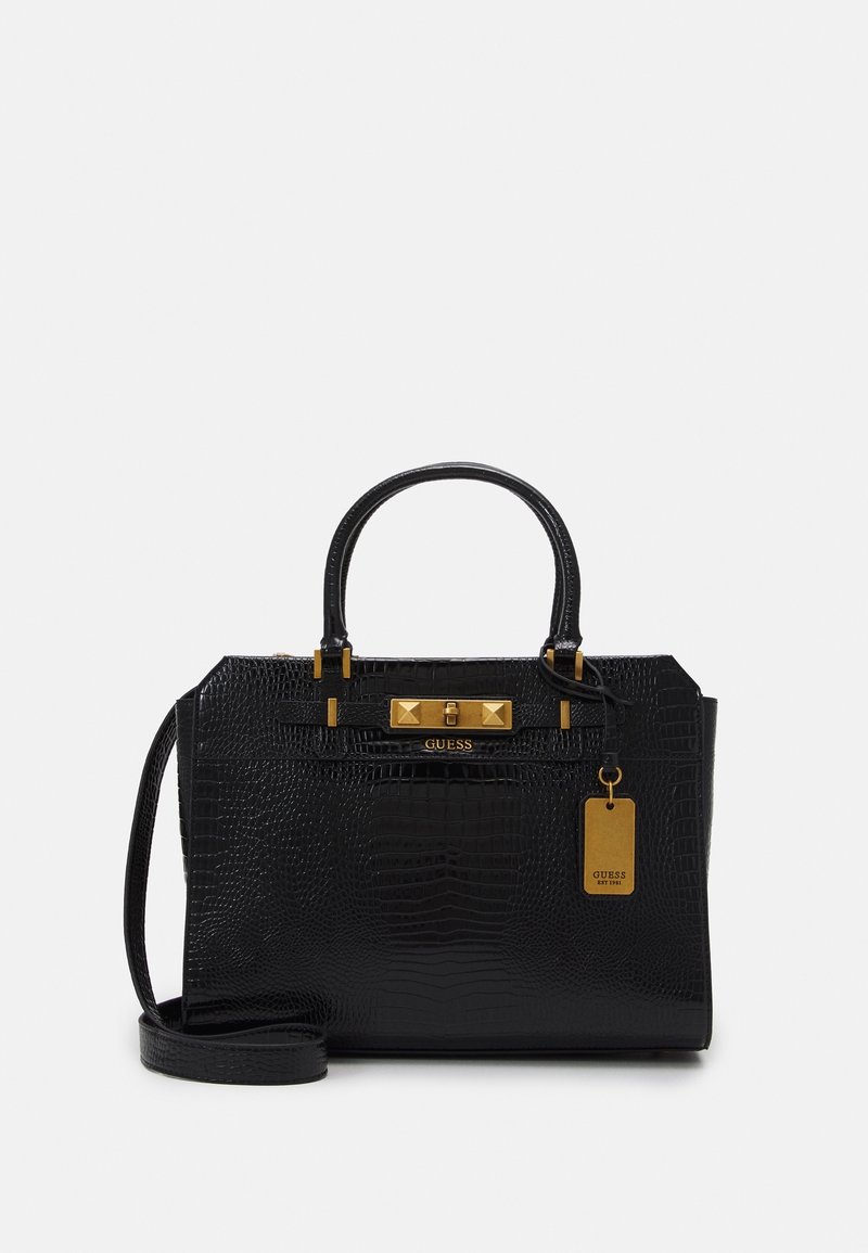 Sac à main en cuir embossé crocodile noir avec double poignée, ferrures dorées, logo GUESS et bandoulière amovible, présenté sur fond blanc.