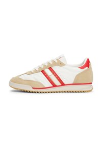 Basket blanche avec des accents en daim beige, des rayures rouges et une semelle en caoutchouc texturée. Présente un design classique à lacets et un détail de logo.