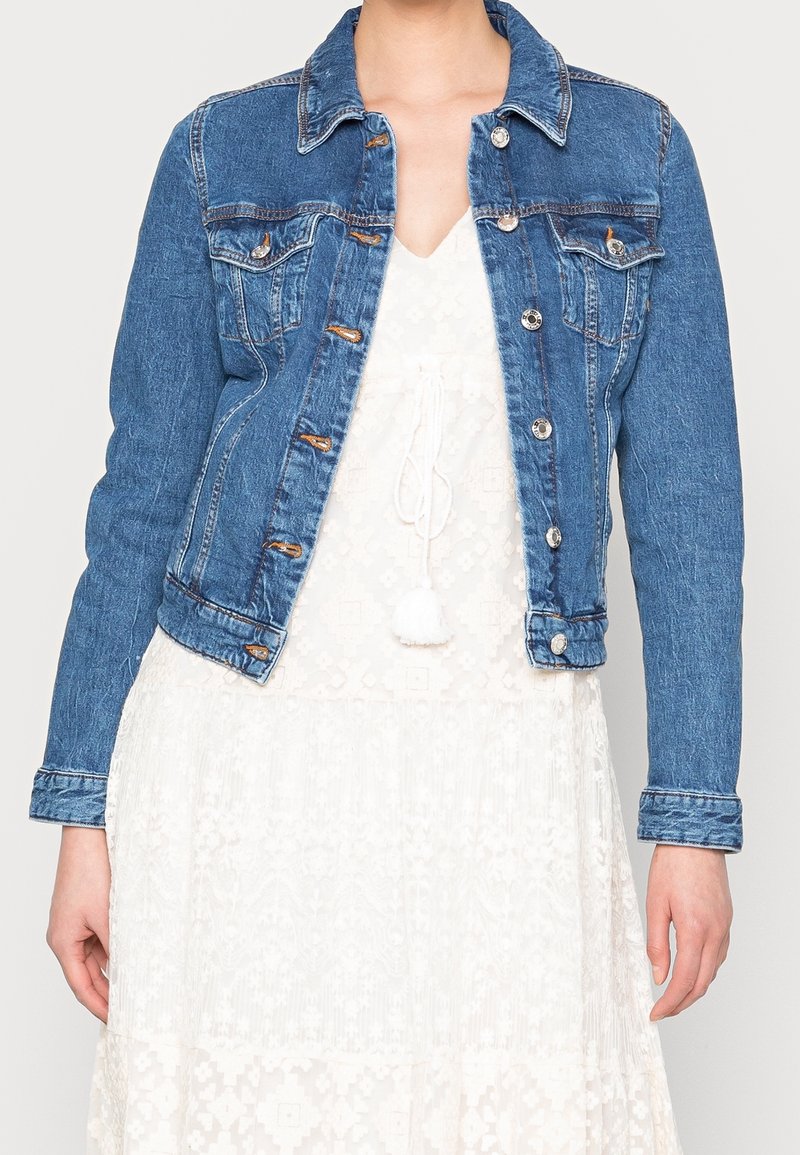 Denimjacka i medelblått med en klassisk passform. Har silverfärgade detaljer, två bröstfickor och en spetsig krage. Texturerat tyg.