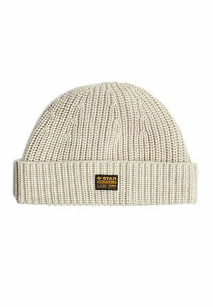 Bonnet tricoté couleur crème avec un revers plié et une petite étiquette noire et jaune G-Star Originals à l'avant.