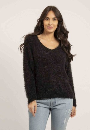 Pull noir en laine bouclée avec un large col en V, coupe ample et manches longues, associé à un jean déchiré bleu clair. Texture douce et design décontracté.