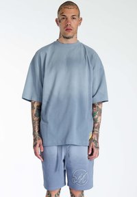 Grå-gradient oversized t-shirt med dropped shoulders, parret med matchende shorts med et broderet logo. Materiale i bomuldsblanding.