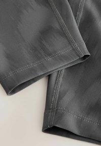 Gray athletic shorts made from a smooth, stretchy fabric with subtle gradient patterns. Features flat seams and a folded hem.