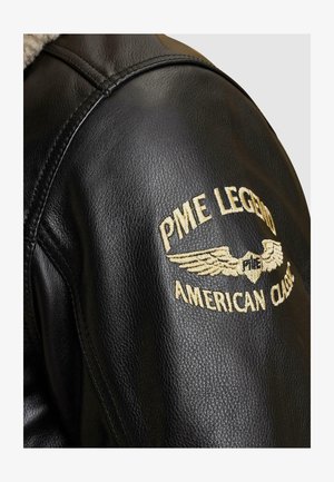 Schwarze Lederjacke mit gestickten Details. Gesticktes Logo auf der Schulter mit Flügel-Design in Gold, das Markennamen und Stil anzeigt.