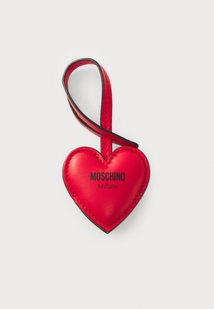 Rød lær hjerteformet nøkkelring med en svart akcentstropp. Har "MOSCHINO" og "Milano" trykt i svart. Glatt tekstur.