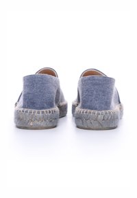 Espadrilles de denim de color azul claro, con una textura suave y suelas de yute trenzado. El diseño presenta una parte trasera redondeada sin soporte para el talón.