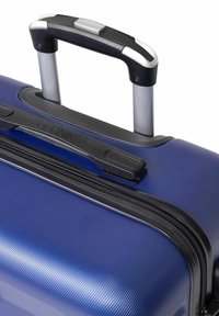 Niebieska twarda walizka z teksturowaną powierzchnią, czarną teleskopową rączką i zamknięciem na zamek u góry.