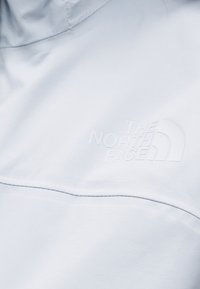 Svetlomodrá bunda z mäkkej tkaniny. Má tónované logo "THE NORTH FACE" a dizajn goliera. Hladká textúra s minimom švov.