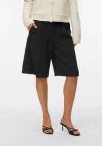 Kullgrå skreddersydde shorts med løs passform, med en regelsdesign og sidelommer, parret med svarte hæl-sandaler.