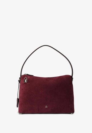 Bordeaux suède handtas met een gebogen leren handvat, zilverkleurige hardware, een ritssluiting en een klein hangertje. Platte rechthoekige vorm.