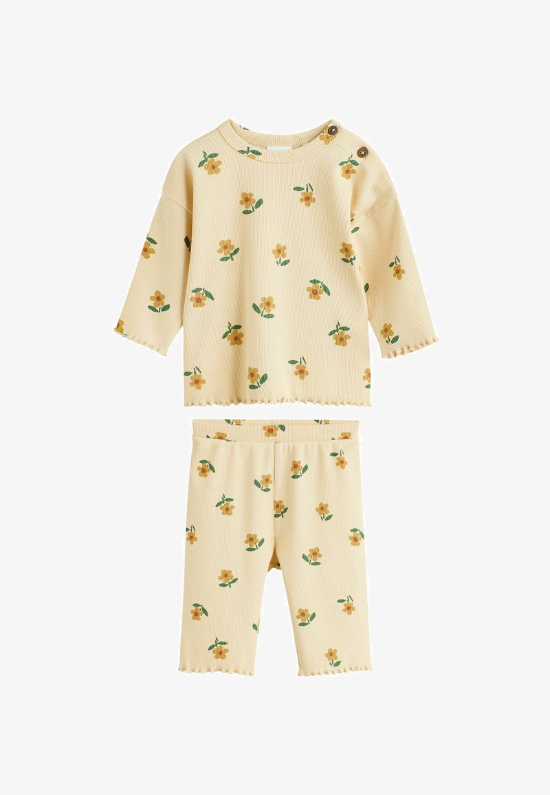 Dzeltena ribota divdaļīga komplekta daļa, kas ietver augšu ar ziedu rakstu, apaļu kaklu un pogu detaļām; šortus ar elastīgu jostasvietu un ziedu akcentiem.