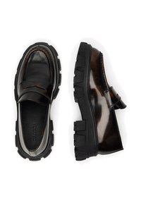 Czarne błyszczące mokasyny z grubą gumową podeszwą i ozdobnym paskiem. Gładka faktura powierzchni i precyzyjne przeszycia. Wnętrze z widocznym logo marki.