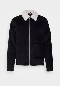 Svart kordjacka med en vit faux fur-krage. Har en framzipper och två stora framfickor. Ribbad muddar och nederkant.