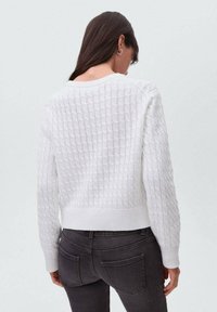 Weißer gestrickter Pullover mit einem strukturierten Gittermuster, Rundhalsausschnitt und geripptem Saum. Trägt man über dunklen Jeans, von hinten betrachtet.