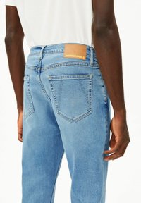 Hellblaue Jeans aus Denim mit einem Leder-Rückenpatch mit "ARMEDANGELS"-Markenlogo, fünf Taschen und einem klassischen geraden Schnitt.