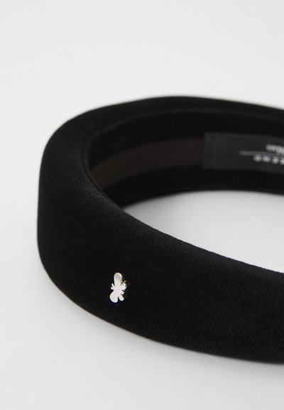 Svart tygband med en slät textur, rund form och silverdetalj med en liten emblem på sidan.