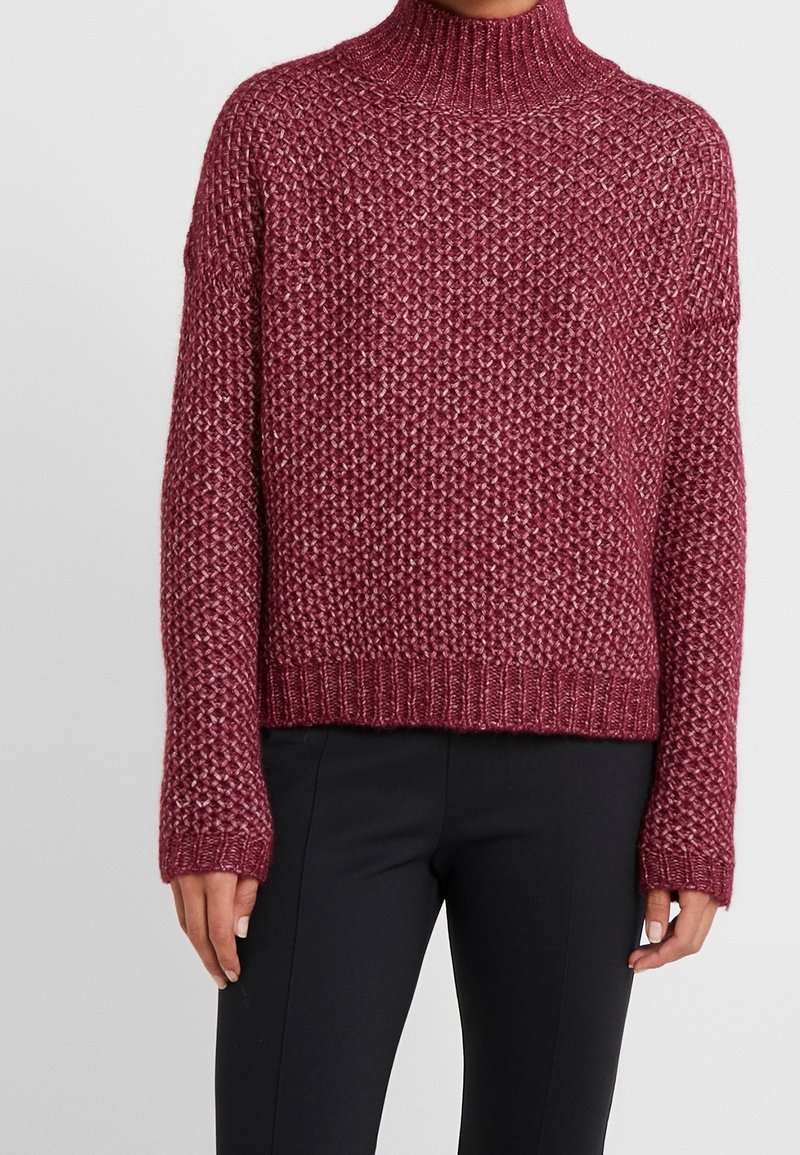 Maglione lavorato a maglia color maroon con colletto alto, motivo testurizzato e maniche lunghe. Orlo e polsini a coste, progettato per una vestibilità comoda.