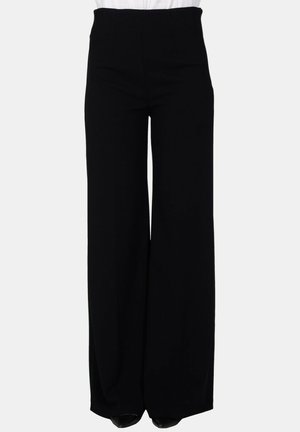 Pantaloni neri a vita alta e gamba larga, indossati con un top bianco infilato, mostrati dalla vita ai piedi su uno sfondo semplice.
