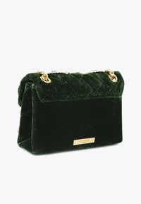 Groene fluwelen handtas met een quilted ontwerp, voorzien van gouden hardware en een zilveren kettingriem. Merk metalen plaatje aan de voorkant.