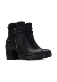 Botas de tobillo de cuero negro con un alto tacón cuadrado, con parte superior arrugada, detalle de cremallera, forro suave y suela texturizada.
