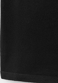 Gros plan d'un tissu tricoté côtelé noir avec un ourlet plié sur le bord inférieur.