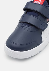 Chaussure en cuir synthétique bleu marine avec accents blancs, bandes à scratch, bout rond et semelle texturée. Marque visible sur la bande.