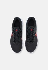 Czarne buty sportowe z siateczkową cholewką, szarymi akcentami, różowym logo w kształcie pioruna i czarnymi sznurowadłami. Biała środkowa podeszwa i gumowa podeszwa.