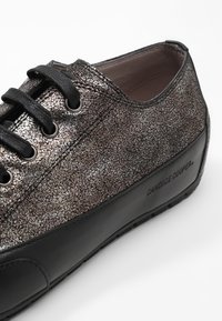 Baskets à texture métallique avec des lacets noirs, une semelle noire et le logo "CANDICE COOPER" sur le panneau latéral.