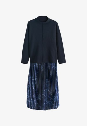 Tengerészkék felső magas nyakkal és lehajtott vállakkal, sötét virágmintás, pliszírozott szoknyával párosítva. Puha anyag, hétköznapi kialakítás.