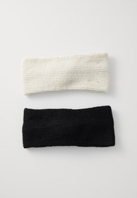 Set di due fasce per la testa in maglia: una colore avorio, l'altra nera. Entrambe presentano un motivo texturizzato a coste con un design ampio per comfort e calore.