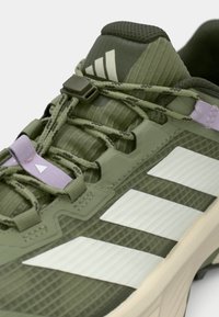 Πράσινο αθλητικό παπούτσι με υφή υλικού, εμφανείς λευκές ρίγες, ρυθμιζόμενο σύστημα κορδονιών και επενδεδυμένη γλώσσα για άνεση.