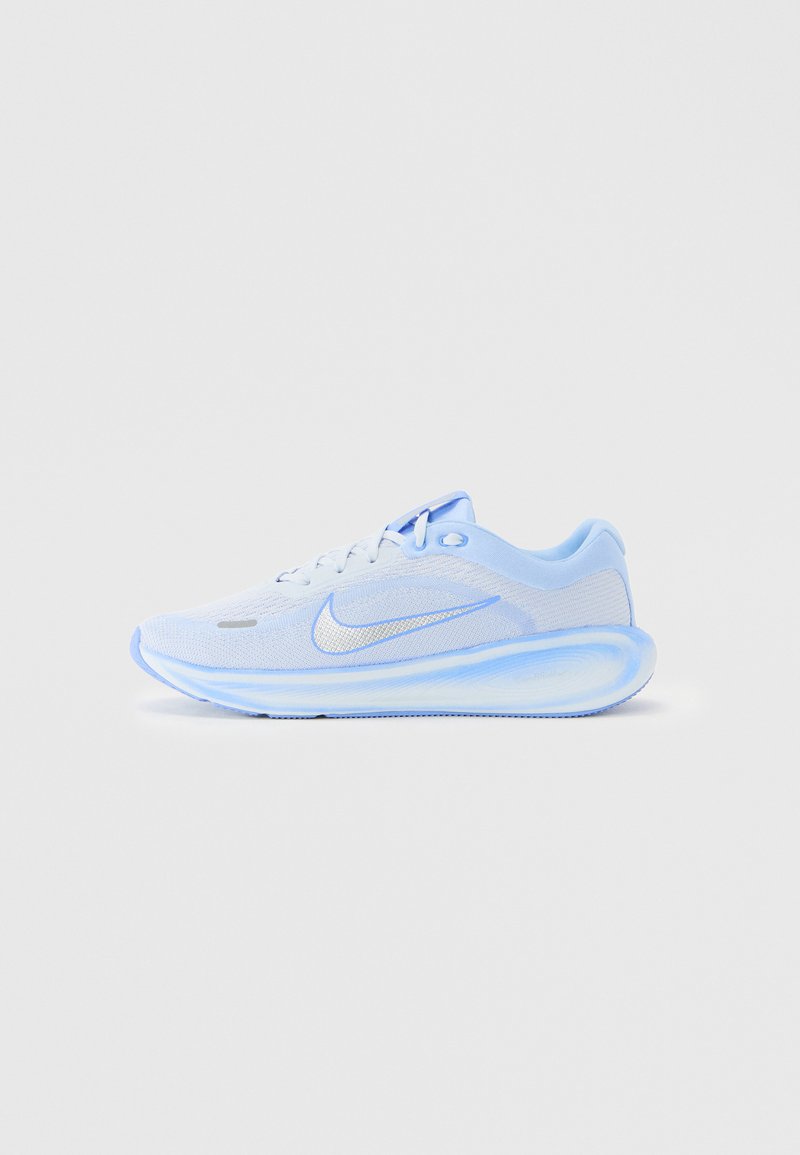 Zapatilla de running Nike en azul claro y blanco con parte superior de malla, suela acolchada y logo de swoosh de Nike en el lateral, sobre un fondo liso.