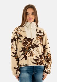 Pullover in fleece con un motivo floreale nei toni crema, marrone e verde, dotato di un colletto alto, chiusura a mezza zip e tasca frontale.