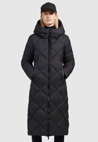Black quilted longer puffer coat with a high collar, front zipper, and two side pockets. Features a hood and a subtle brand logo detail.
