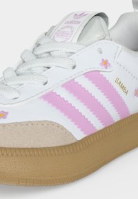 Λευκό παπούτσι Adidas Samba με ροζ ρίγες, μικρές ροζ λεπτομέρειες με λουλούδια, μπεζ γαζωμένη μύτη και γνήσια λαστιχένια σόλα.