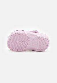 Rosa skumsula på träskor med texturerat mönster, med justerbar rem och logotypdetalj. Gummimaterial med slät yta.