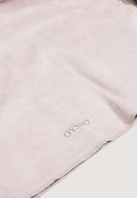 Světlé fialové sametové látka s hladkým povrchem; má prošitou hranu a logo v pravém dolním rohu.