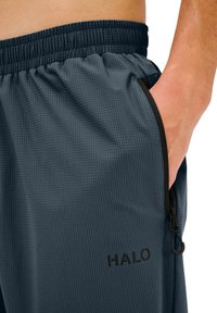 Donkergrijze heren shorts met een gestructureerd patroon, elastische tailleband en zijzak met zwarte rits. Inclusief zwart "HALO" logo.